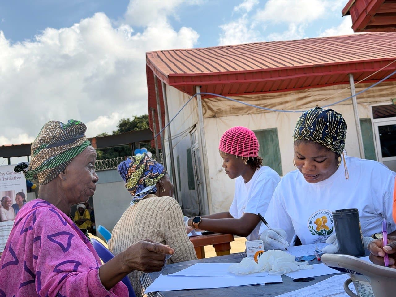 Healthcare workers assisting an elderly man during a community health outreach in ijede, lagos,Nigeria
